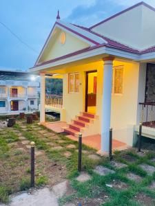 una pequeña casa amarilla con porche en Silver Mist villa, en Kodaikanal