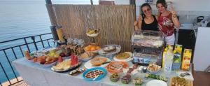 two women standing next to a table of food at Dolce Vita Rooms and Apartments in Cefalù
