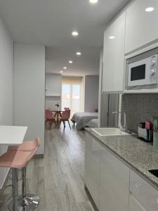 a kitchen with white cabinets and a living room at Apartamentos Antequera in Antequera