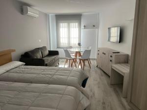 Apartamentos Antequera في أنتيكيرا: غرفة نوم بسرير وطاولة واريكة