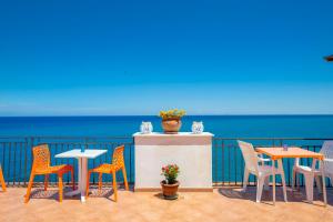 a patio with tables and chairs and the ocean at Dolce Vita Rooms and Apartments in Cefalù