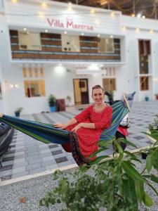 a woman sitting in a hammock in front of a building at VILLA MANTRAA in Varkala