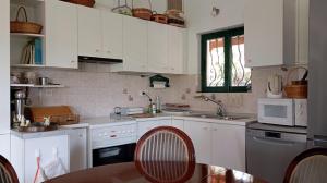 - une cuisine avec des placards blancs, une table et des chaises dans l'établissement Entire cottage near the beach in Nimporio, Euboea, à Animborió