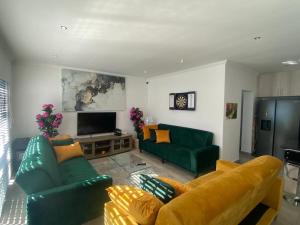 a living room with a green couch and a television at 32 On Gill Road Self Catering in Cape Town