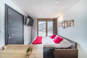a bedroom with a bed with pink pillows on it at Résidence Kocoon Les Karellis - Skipass inclus in Montricher-Albanne