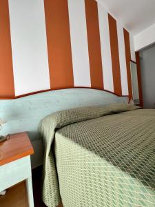 a bedroom with a bed with a striped wall at Hotel Soleado in Taormina