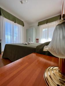 a bedroom with a bed and a table with a lamp at Hotel Soleado in Taormina