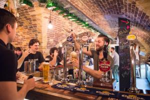 un hombre de pie en un bar sosteniendo una bebida en Wombat's City Hostel London, en Londres