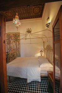 a bedroom with a large white bed with a chandelier at Dar Dalila Fes in Fez