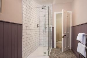 ein Bad mit einer Dusche und weißen Fliesen in der Unterkunft Laurel Cottage in Cockburnspath + 22 Fotos