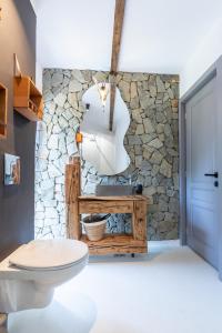 a bathroom with a white toilet and a stone wall at Bransilvania Fantasy Boutique Chalet - Adults Only in Bran