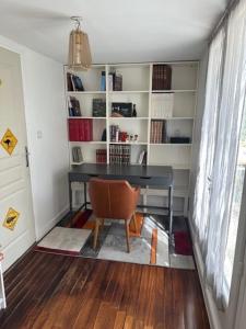 a desk and a chair in a room with a book shelf at Appartement dans résidence calme dans les Monts du Lyonnais in Soucieu-en-Jarrest