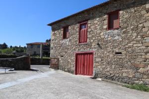 um edifício de pedra com uma porta vermelha e janelas em Casa-museo Genia Trigo em Sober