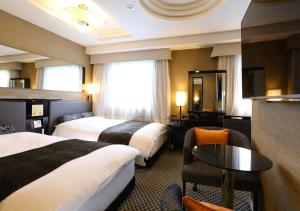 東京にあるアパホテル〈上野駅北〉のベッド2台とテーブルが備わるホテルルームです。