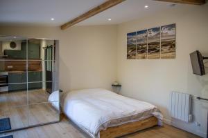 a bedroom with a large bed and a kitchen at Charmant studio in Saint-Aubin-de-Médoc