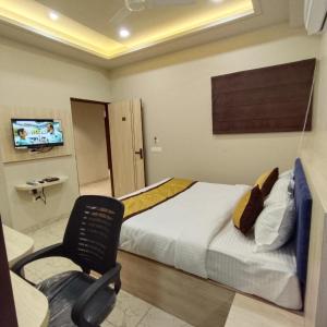 a bedroom with a bed and a chair and a television at HOTEL SNOOZE in Jaipur