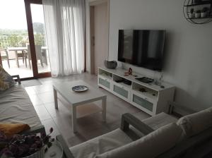 uma sala de estar com uma televisão, um sofá e uma mesa em Residencial Xeresa del Monte Solo Familias Serviplaya em Jeresa