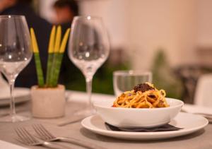 a bowl of pasta on a table with wine glasses at Alfons Hotel in Ciutadella