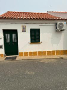 um edifício branco com portas verdes e uma janela em Casa dos AVÓS em Santana de Cambas