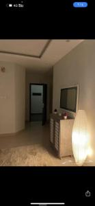 uma sala de estar com televisão e uma mesa com candeeiro em شقة مودرن مرتبة الرياض الحمراء em Riade