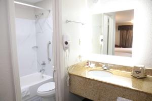 a bathroom with a sink and a toilet and a mirror at Days Inn by Wyndham Monroe in Monroe