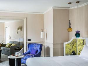 een slaapkamer met een bed en een blauwe stoel en een bank bij Sofitel Le Scribe Paris Opera in Parijs