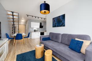 a living room with a gray couch and a kitchen at Flaminga Two-Level Apartment in Szczecin