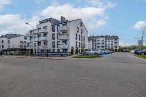 un gran edificio blanco con coches aparcados en un aparcamiento en Flaminga Two-Level Apartment, en Szczecin