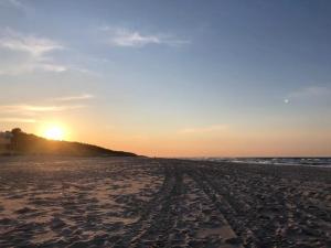 a beach with the sun setting in the distance at Apartament Juratka in Jurata