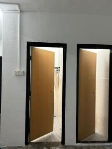 two brown doors in a bathroom with a shower at RumaDino Homestay in Melaka