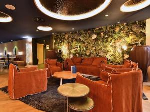 uma sala de espera com cadeiras laranja e uma parede com plantas em ibis Styles Nantes Reze Aéroport em Rezé