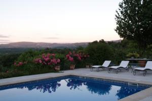 una piscina con 2 sillas y flores rosas en Finca A Coutada., en Celanova