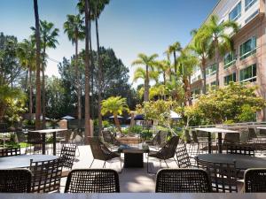 圣地亚哥DoubleTree by Hilton San Diego Del Mar的一个带桌椅的户外庭院,棕榈树