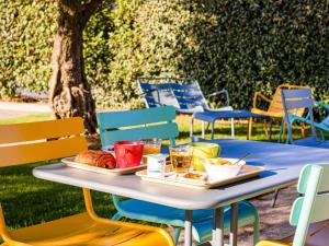 - une table avec un plateau de nourriture et des chaises dans l'établissement ibis budget Carcassonne Aéroport - A61, à Carcassonne