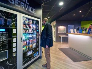 a man standing in front of a vending machine at ibis budget Cholet Centre in Cholet