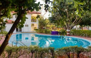 una piscina frente a una casa con árboles en Hridey Retreat Resort en Rāmnagar
