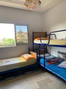 2 Etagenbetten in einem Zimmer mit Fenster in der Unterkunft Appartement RESIDENCE « RAYANE BEACH » in Sidi Rahal