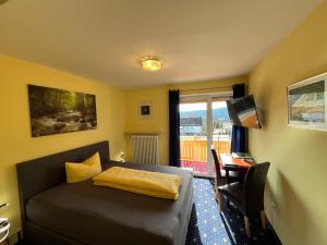 a bedroom with a bed and a desk and a window at Pension Elan in Bayerisch Eisenstein