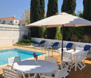 a table with an umbrella next to a swimming pool at Villa Kiveli in Ayia Napa