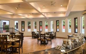 un comedor con mesas, sillas y ventanas en Hridey Retreat Resort, en Rāmnagar