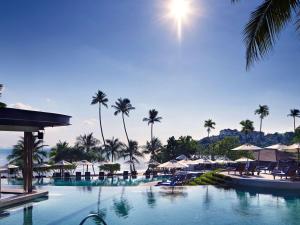 攀瓦海灘的住宿－Pullman Phuket Panwa Beach Resort，一个带椅子和遮阳伞的游泳池以及棕榈树