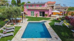 un patio trasero con piscina y una casa rosa en L'Organetto, Luxury B&B en Lido di Fermo