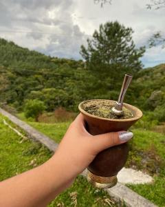 uma mão segurando um copo com uma colher dentro em Casa de campo em São José dos Pinhais