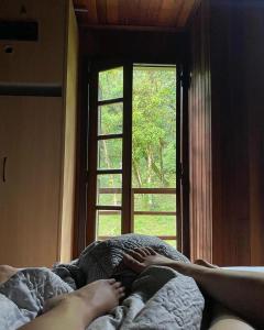 uma pessoa deitada na cama em frente a uma janela em Casa de campo em São José dos Pinhais