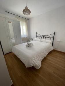 Un dormitorio con una cama blanca con un animal de peluche. en El caserío de la abuela, en Cabezuela del Valle