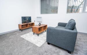 - un salon avec une chaise, une télévision et une table dans l'établissement Bright and Modern 1 Bed Apartment in Redditch, à Redditch