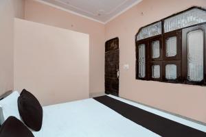 1 dormitorio con cama blanca y ventana en SPOT ON guest house en Bulandshahr