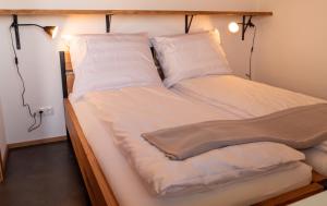 een groot bed met witte lakens en kussens bij Kellerstöckl am Berg in Eisenberg an der Pinka