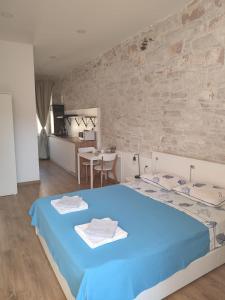 a bedroom with a blue bed and a stone wall at Central Studio Apartment in Pula