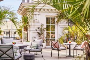 a patio with chairs and tables and palm trees at Hyatt Centric Gran Via Madrid in Madrid